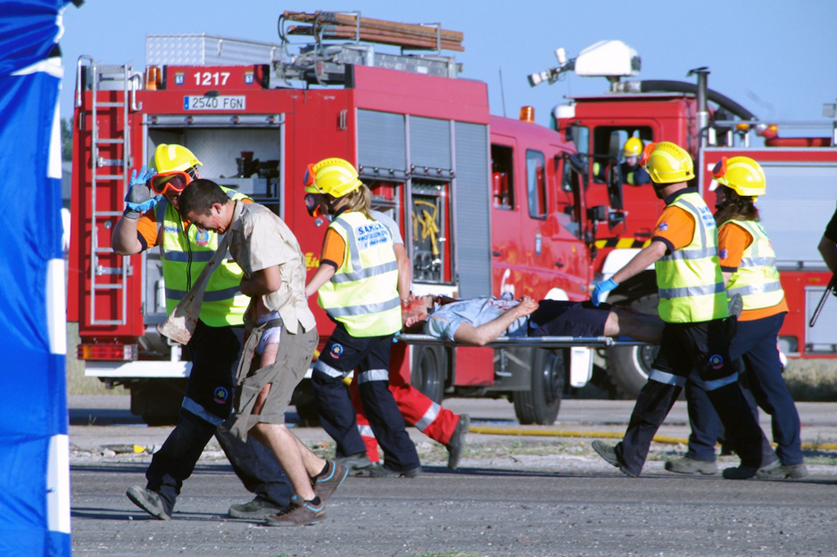 Coche de bomberos, sanitarios llevando paciente en camilla (simulacro)